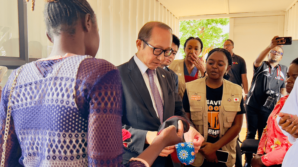 H.E. Nishimaki is shown a reusable sanitary pad, as participants share how they are learning to make these products to support women in the refugee camp. UNFPA/Namibia